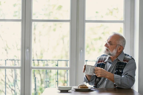 Melancholische grootvader eten ontbijt helemaal alleen aan tafel — Stockfoto