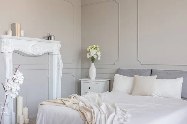 Flowers on nightstand table in delightful bedroom interior with grey and white design — Stock Photo, Image