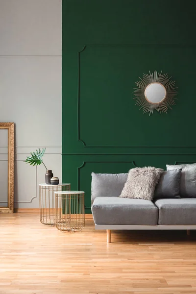 Sun shape mirror on empty green wall in stylish living room interior