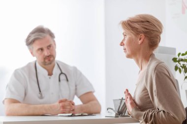 Yakışıklı orta yaş doktor ve kadın hasta hastane ofisinde