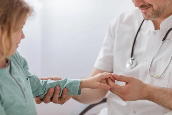 Gros plan du médecin contrôlant la main de l'enfant à l'hôpital — Photo