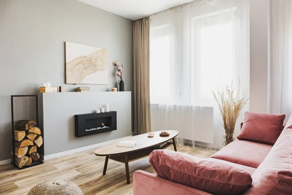 Stilfuld stue interiør med pastel pink sofa, træ sofabord og øko pejs - Stock-foto