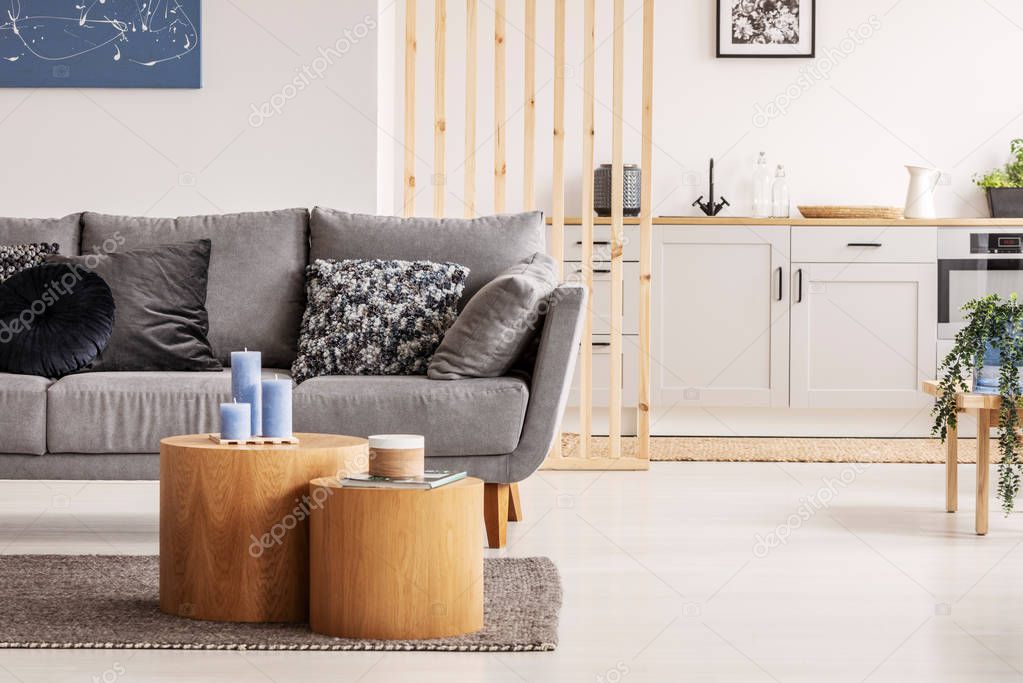 Two wooden block shape like coffee tables with kinck knacks in front of grey scandinavian sofa with pillows