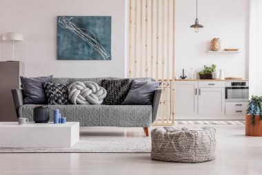 Açık plan oturma odası ve beyaz dolaplar ve yastık ile gri kanepe ile mutfak iç