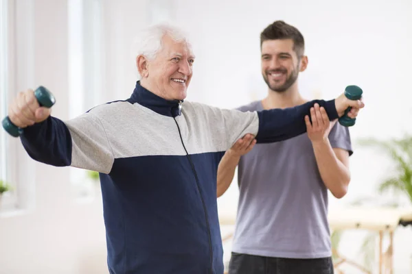 Senior férfi stroke után az idősek otthonában gyakorlása hivatásos gyógytornász — Stock Fotó