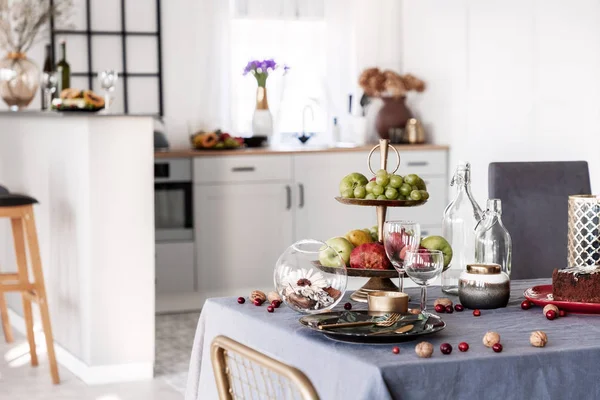 Nuts, grapes and apples on dining table with wine glasses and plate with tableware — Stock Photo, Image