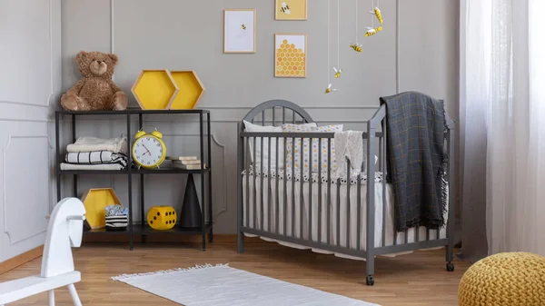 Installation with yellow and black bees above grey wooden crib with blanket and pillow — Stock Photo, Image