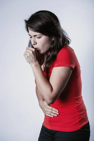 赤いTシャツを着て咳をする若いかわいいブルネットの女性 — ストック写真