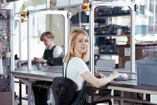 Pretty female student wearing green overall doing practical work at factory — Stock Photo, Image
