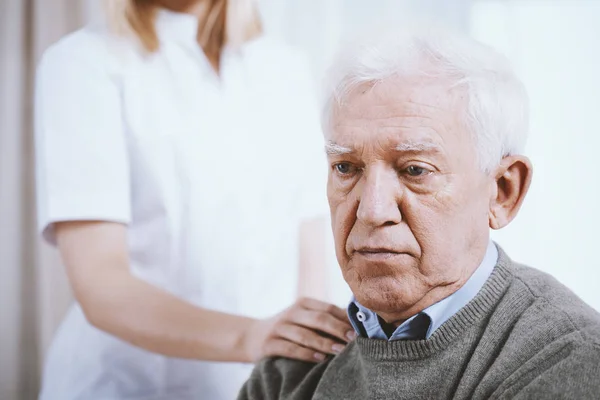 Portret van senior man met hand van ondersteunende verpleegkundige op zijn schouder — Stockfoto