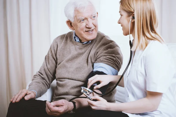 Senior grey man with supporting measuring blood pressure — Stock Photo, Image