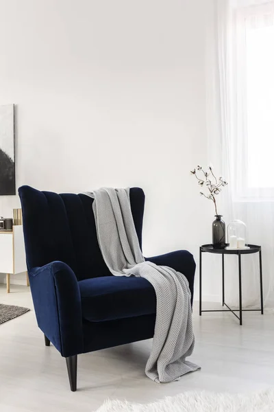 Σκούρο μπλε βελούδο πτέρυγα πίσω καρέκλα με γκρίζα κουβέρτα στο μοντέρνο σαλόνι — Φωτογραφία Αρχείου