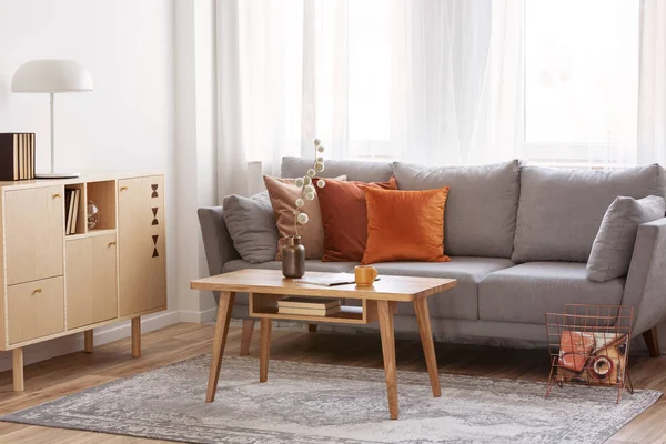 Retro wooden coffee table in front of grey couch in classy living room interior — Stock Photo, Image