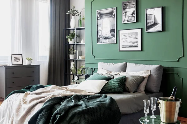Gallery of black and white poster on green wall behind king size bed with pillows and blanket — Stock Photo, Image