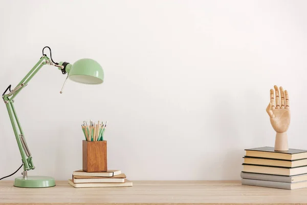 Пастельна м'ята кольорова лампа на дерев'яному столі з книгами, копіювати простір на порожній білій стіні — стокове фото