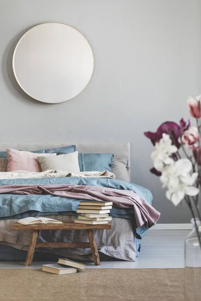 Round mirror in wooden frame on grey wall of elegant bedroom interior with comfortable bed with pastel, blue and pink bedding — Stock Image Round mirror in wooden frame on grey wall of elegant bedroom interior with comfortable bed with pastel, blue and pink bedding Stock Picture