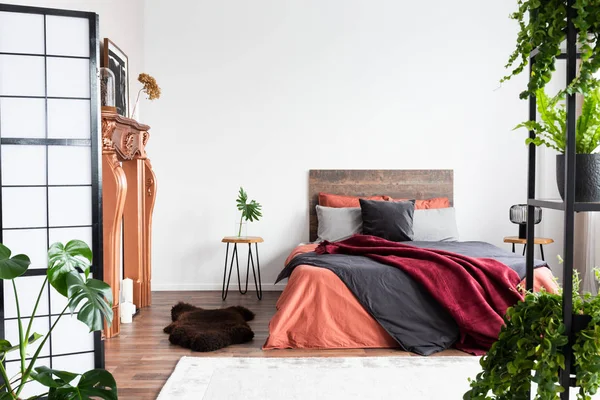 Kopieer ruimte op lege witte muur van rustieke slaapkamer interieur met King size bed met oranje beddengoed en Bourgondische deken — Stockfoto