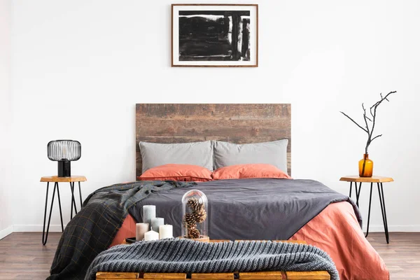 King size bed met oranje en grijs beddengoed tussen twee houten nachtkastje met lamp en vaas — Stockfoto