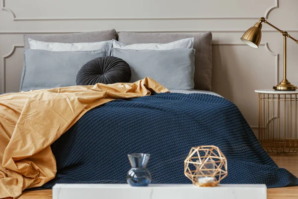 Lámpara dorada en la mesita de noche de moda junto a la cama king size con ropa de cama cómoda —  Fotos de Stock