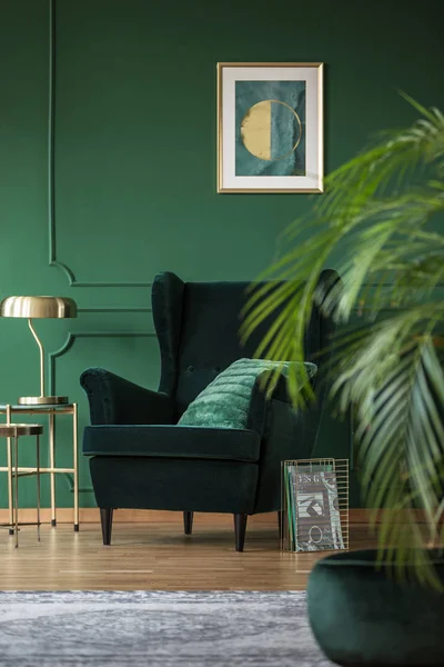 Lámpara dorada sobre mesa elegante junto al sillón de terciopelo verde oscuro — Foto de Stock