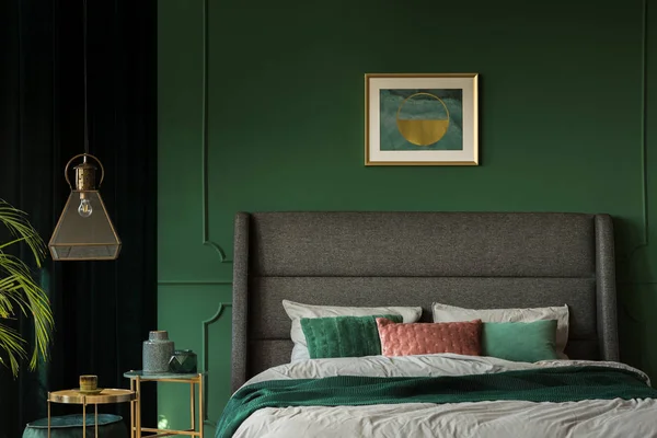 어두운 녹색 침실에서 헤드 보드와 편안한 킹 사이즈 침대 위의 세련된 포스터 — 스톡 사진