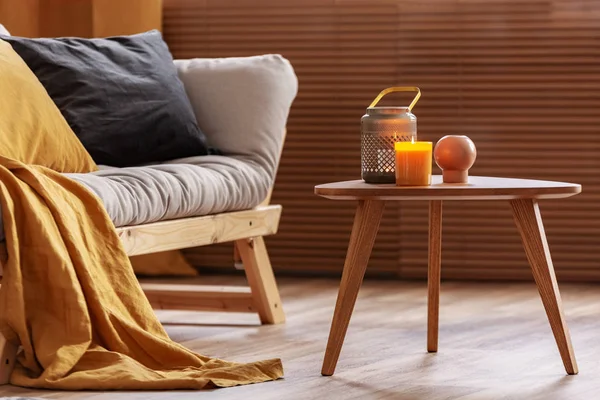 Orange candle on wooden coffee table in cozy living room interior — Stock Photo, Image