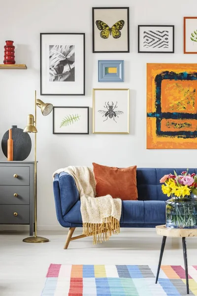 Blanket and pillow placed on navy blue couch standing in white l