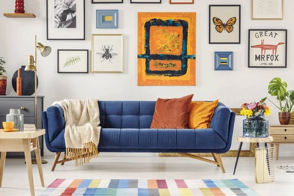 Navy blue couch with bright blanket and two cushions standing in — Stock Photo, Image