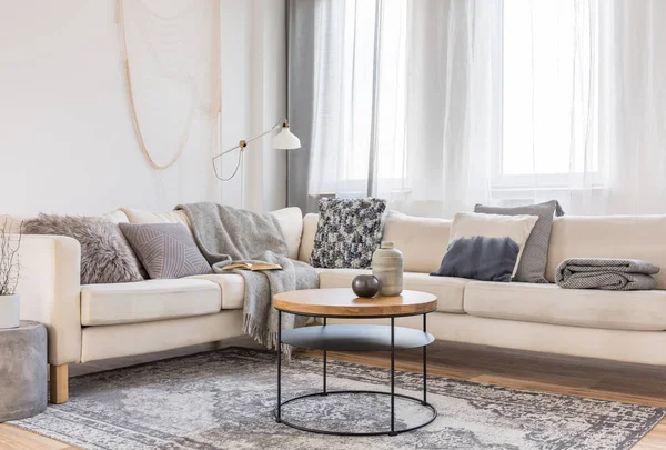 Beige bekväm hörn soffa med grå kuddar i elegant vardags rum interiör med vit vägg — Stockfoto