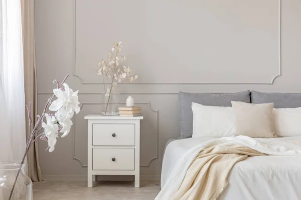 Flores en la mesa de noche en el encantador interior del dormitorio con diseño gris y blanco —  Fotos de Stock