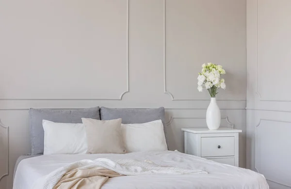 鲜花在白色木制床柜表豪华卧室内部与特大号床 — 图库照片