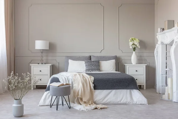 Flores en la mesa de noche en el encantador interior del dormitorio con diseño gris y blanco — Foto de Stock