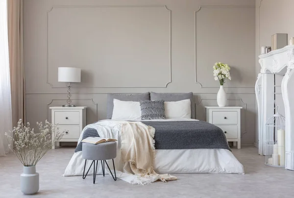 Fiori sul comodino in delizioso interno camera da letto con design grigio e bianco — Foto Stock