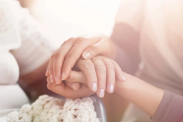 Primer plano de las manos de una joven cogida de la mano de una mujer mayor — Foto de Stock