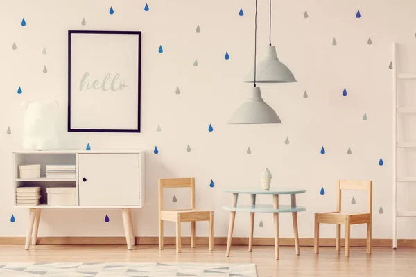 Плакат на стене милой детской комнаты с двумя деревянными стульями за синим столом — стоковое фото