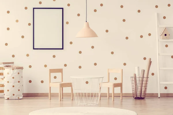 Lampe rose pastel au-dessus d'une petite table blanche tendance avec des chaises en bois dans une chambre scandinave pour enfants — Photo