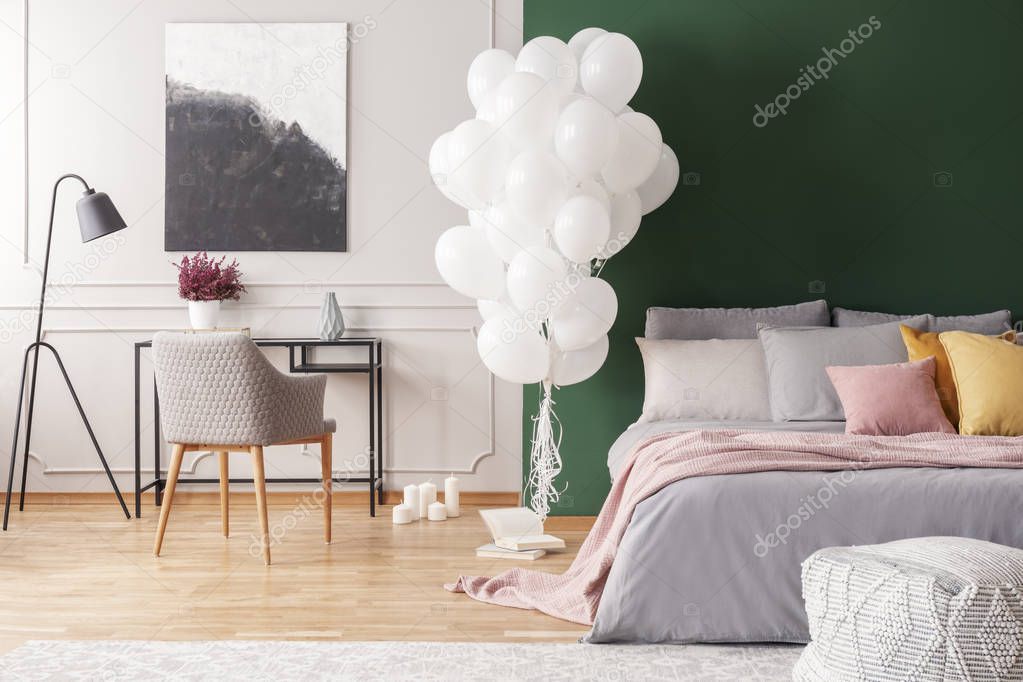 Abstract black and white painting on grey wall of elegant bedroom interior with cozy bed with pillows and blanket