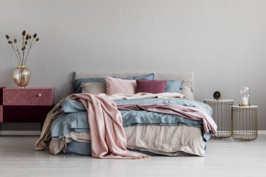 Pastel pembe, bej ve moda yatak odası iç kral yatak üzerinde mavi yatak, boş gri duvarda kopya alanı