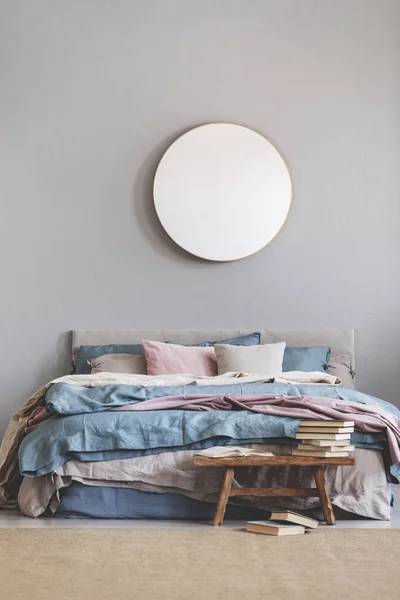 Kerek tükör favázas szürke falon elegáns hálószoba belső kényelmes ágy pasztell, kék és rózsaszín ágynemű — Stock Fotó