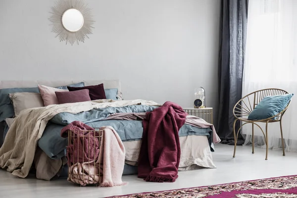Travesseiros coloridos e manta borgonha na cama confortável no interior do quarto na moda — Fotografia de Stock