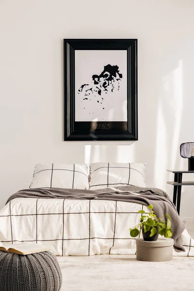 Industrial lamp on nightstand table next to king size bed in white bedroom interior