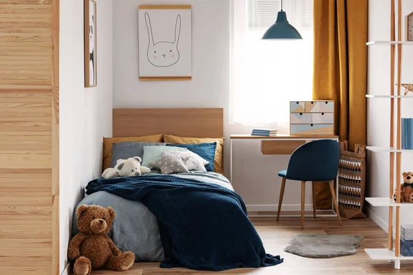 Стол, стул и односпальная кровать с голубыми кроватями в уютном интерьере спальни для детей — стоковое фото