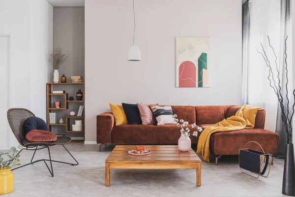 Flores en jarrón sobre mesa de centro de madera en el interior de la sala de estar de moda con sofá de esquina marrón con almohadas y pintura abstracta en la pared —  Fotos de Stock