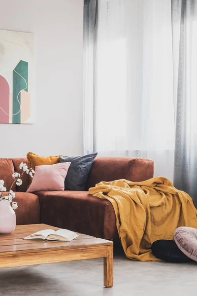 Žlutá přikrývka na hnědé rohové pohovce v moderní obývací místnosti — Stock fotografie