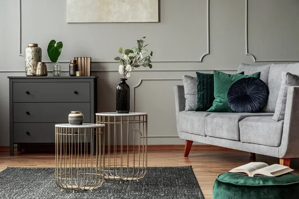 Zwei stylische kleine Couchtische mit Marmorplatten vor einer eleganten grauen Couch mit smaragdgrünen Kissen — Stockfoto