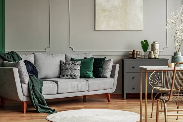 Pillows on long comfortable living room couch in grey scandinavian style interior with wooden floor