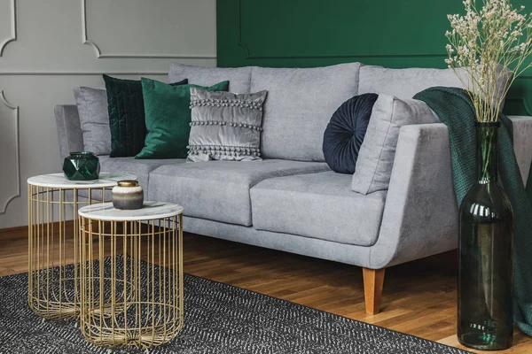Два стильных маленьких журнальных столика с мраморными топами перед элегантным серым диваном с изумрудными подушками — стоковое фото