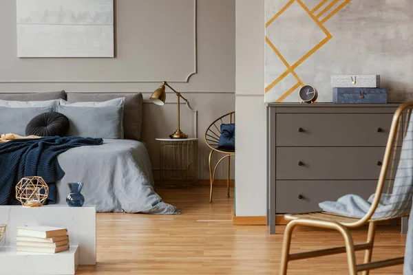 Intérieur de chambre à coucher tendance avec commode grise et chaise dorée — Photo