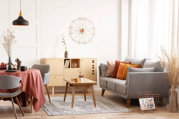 Salon et salle à manger intérieur avec canapé gris et table couverte de nappe orange — Photo