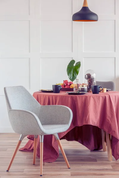 Elegante tavolo da pranzo rivestito con tovaglia zenzero in luminoso soggiorno interno con sedie alla moda — Foto Stock